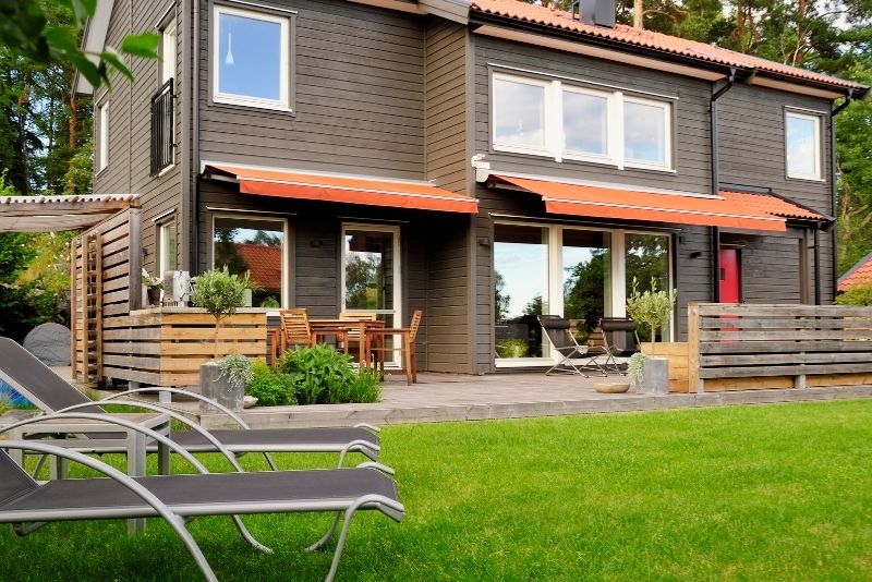 a wooden-walled house and crystal window with patio and timber pergola outside